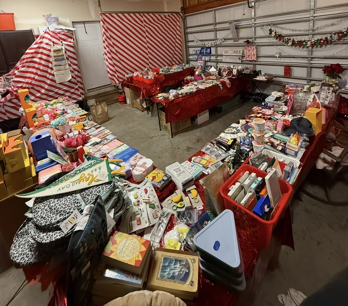 The Cozy Cottage Stocking Shoppe set up in the garage in 2025, with tables of toys, books, and stocking stuffers under Christmas decorations.